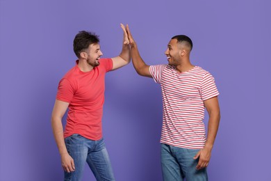 Photo of Men giving high five on purple background