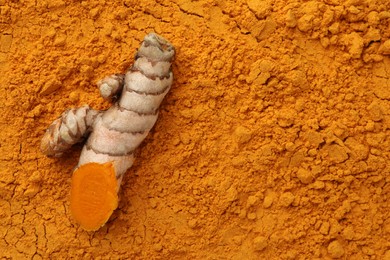 Photo of Cut raw root on aromatic turmeric powder, top view. Space for text