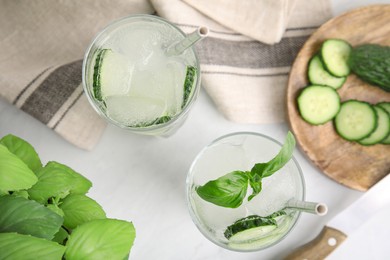 Photo of Tasty fresh cucumber water with basil on white table, flat lay