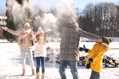 Happy family playing with snow in sunny winter park