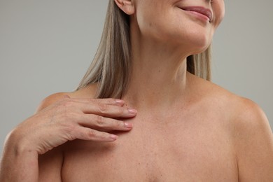 Mature woman with healthy skin on grey background, closeup