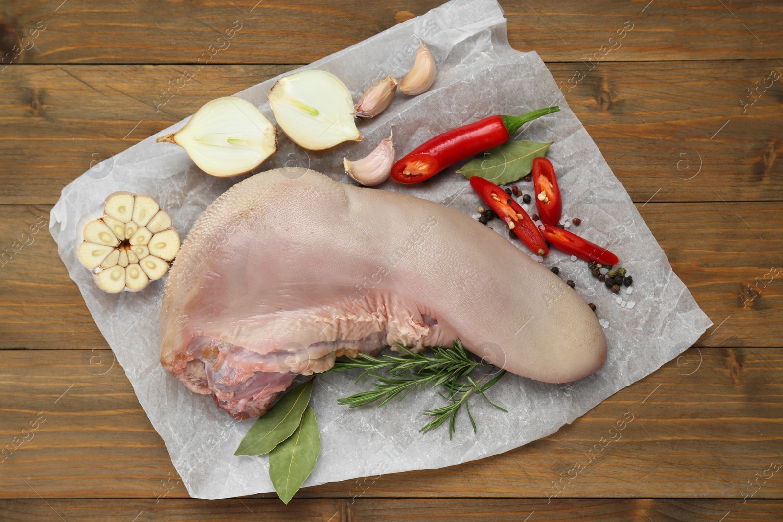 Photo of Parchment with raw beef tongue and products on wooden table, top view