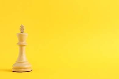 Wooden king on yellow background, space for text. Chess piece