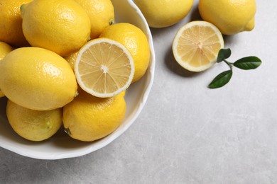 Photo of Fresh lemons and green leaves on grey table, top view. Space for text
