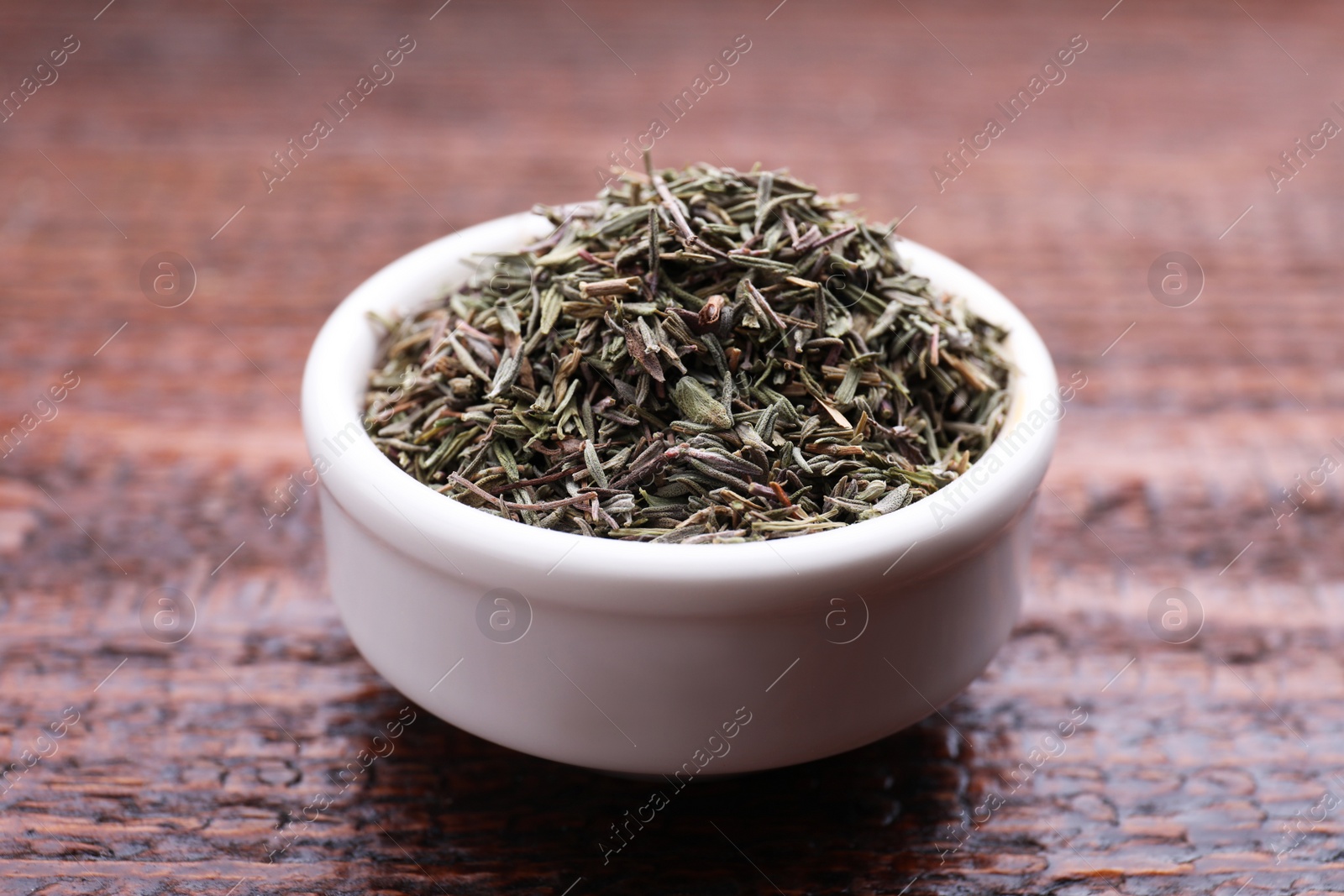 Photo of Bowl with dried thyme on wooden table, closeup