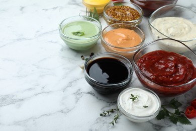 Photo of Many different sauces and herbs on white marble table. Space for text