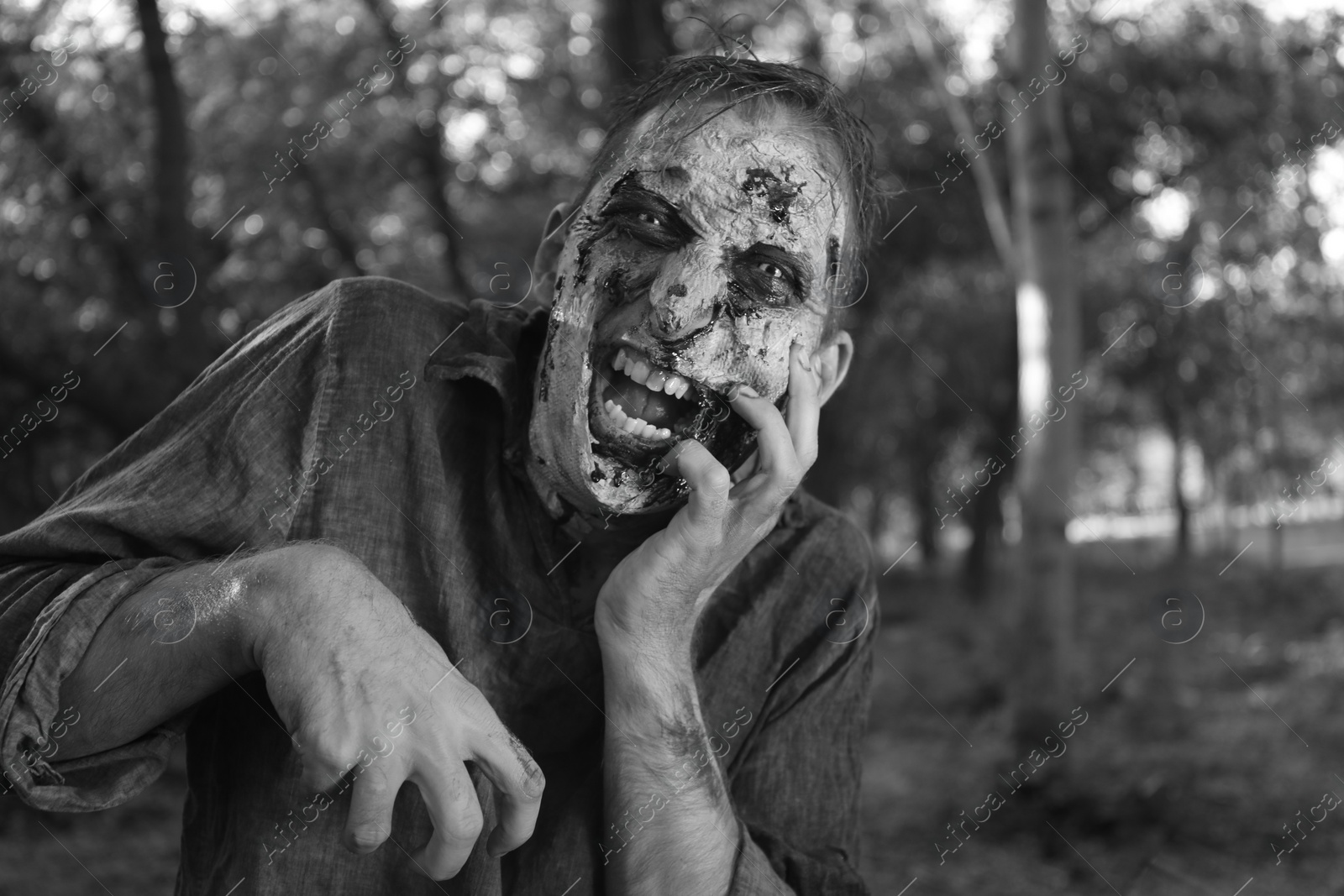 Photo of Scary zombie outdoors, black and white effect. Halloween monster