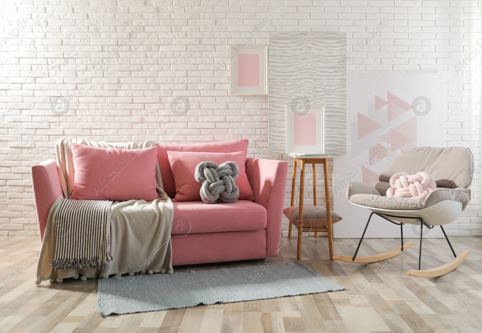 Photo of Stylish living room interior with sofa and rocking armchair near brick wall