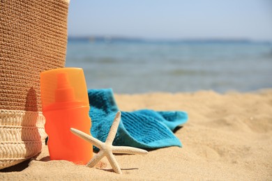Sunscreen, starfish, bag and towel on beach, space for text. Sun protection care