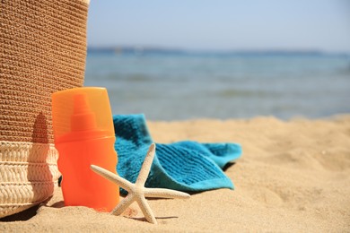 Photo of Sunscreen, starfish, bag and towel on beach, space for text. Sun protection care