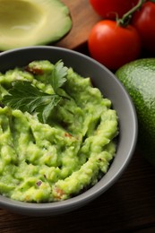 Photo of Delicious guacamole and different ingredients on table, closeup