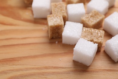 Photo of White and brown sugar cubes on wooden table, closeup. Space for text