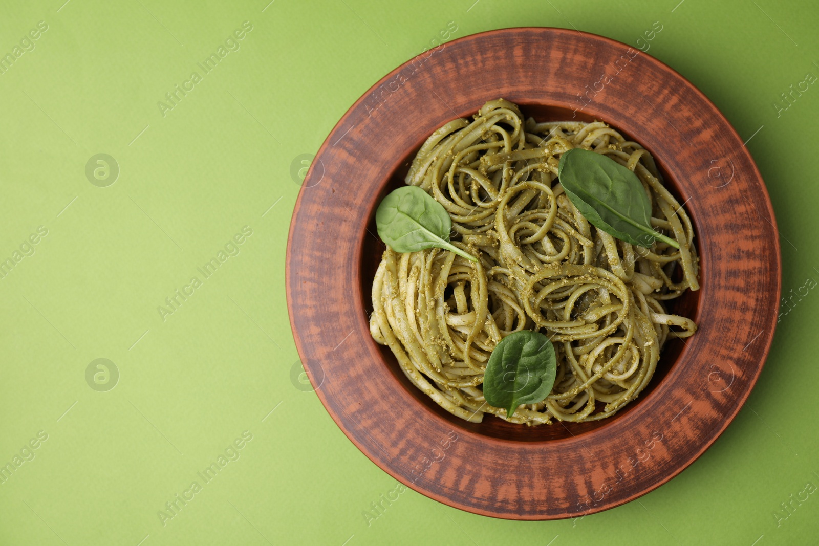 Photo of Tasty pasta with spinach on green table, top view. Space for text