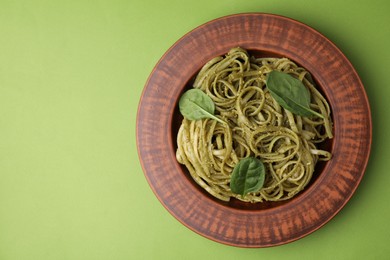 Photo of Tasty pasta with spinach on green table, top view. Space for text