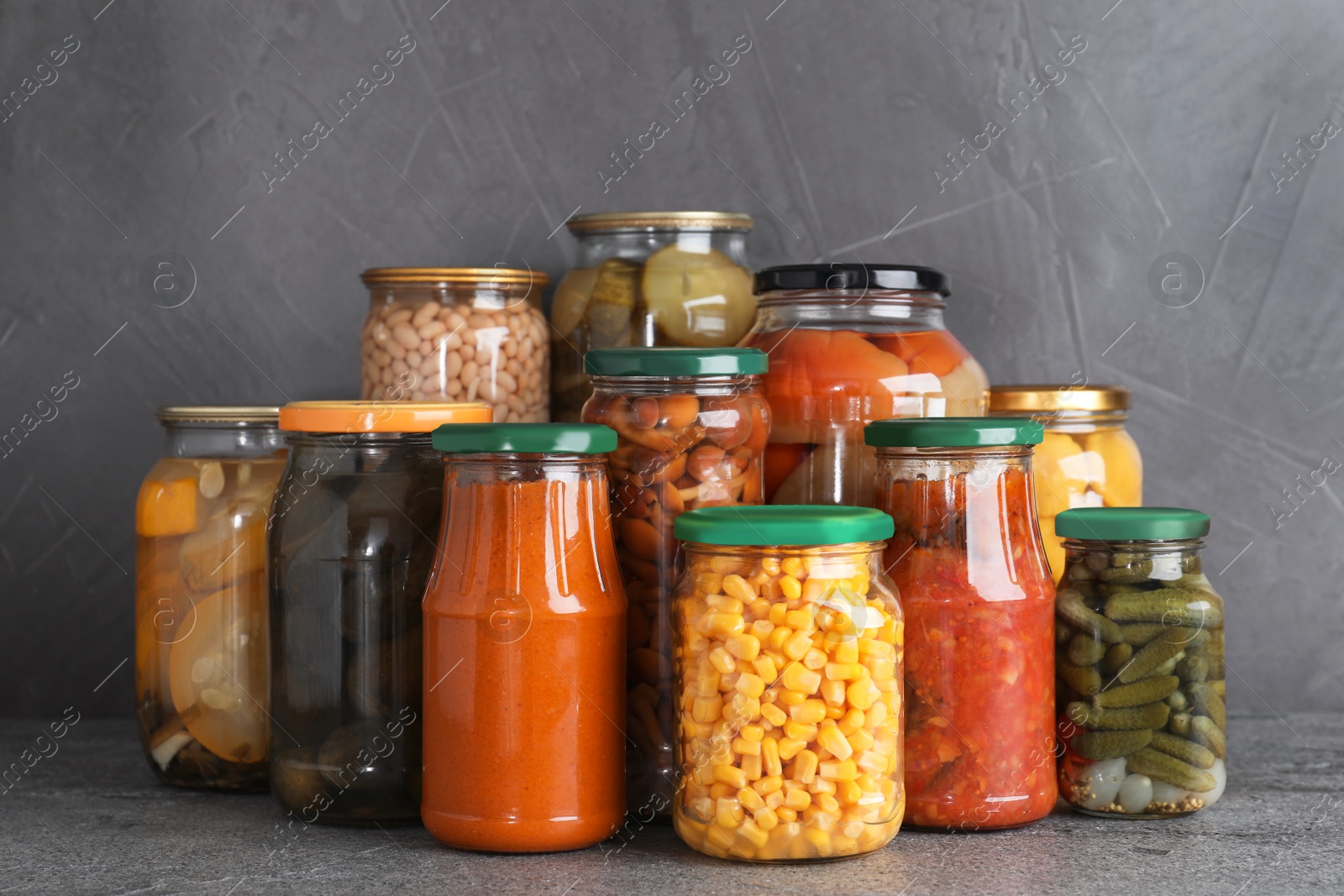 Photo of Jars of tasty pickled vegetables on grey table