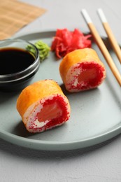 Photo of Delicious sushi rolls, soy sauce, wasabi, ginger and chopsticks on grey textured table, closeup