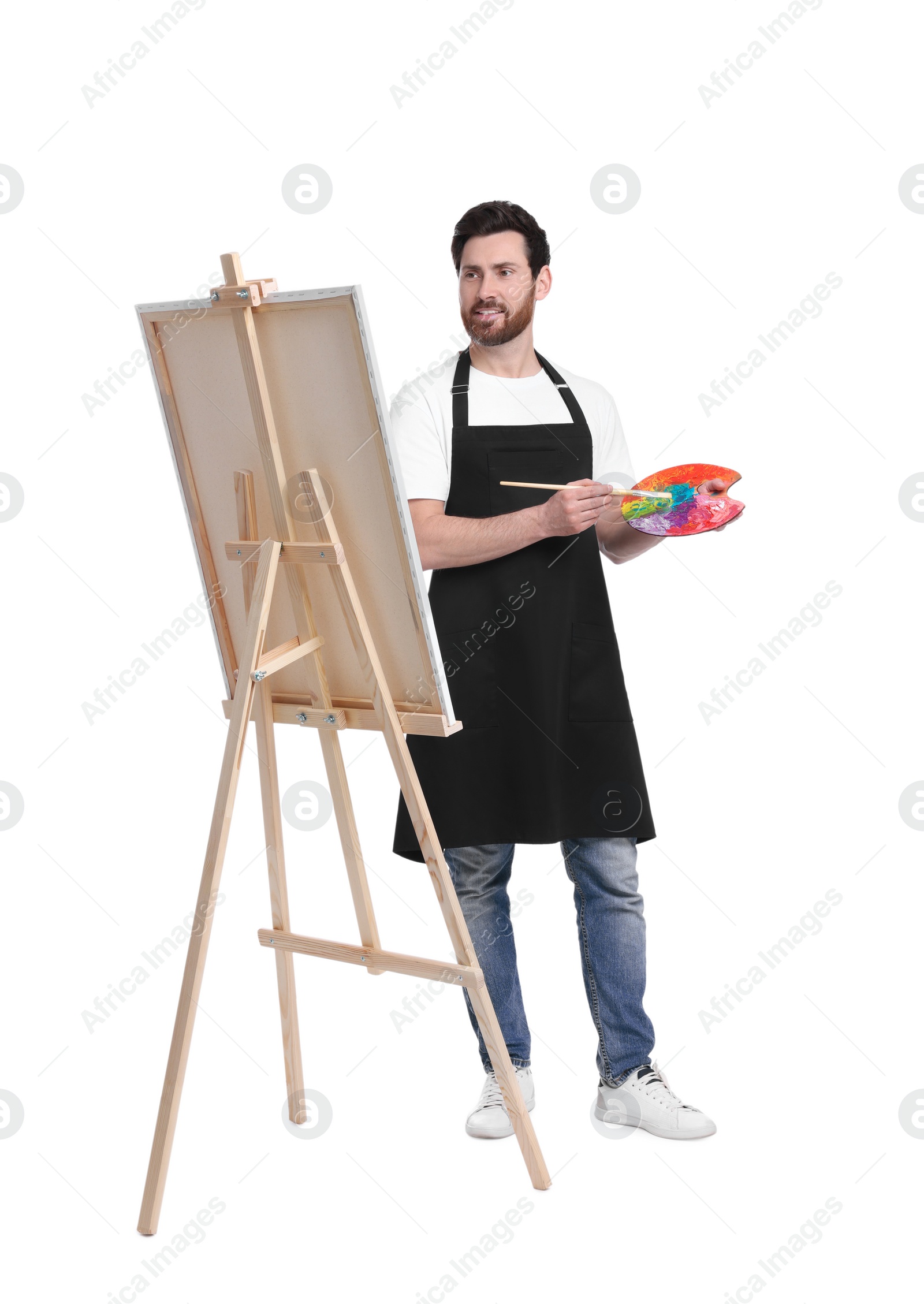 Photo of Artist with brush painting against white background. Using easel to hold canvas