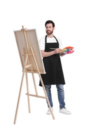 Artist with brush painting against white background. Using easel to hold canvas