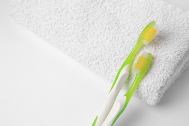 Photo of Light green toothbrushes and terry towel on white background