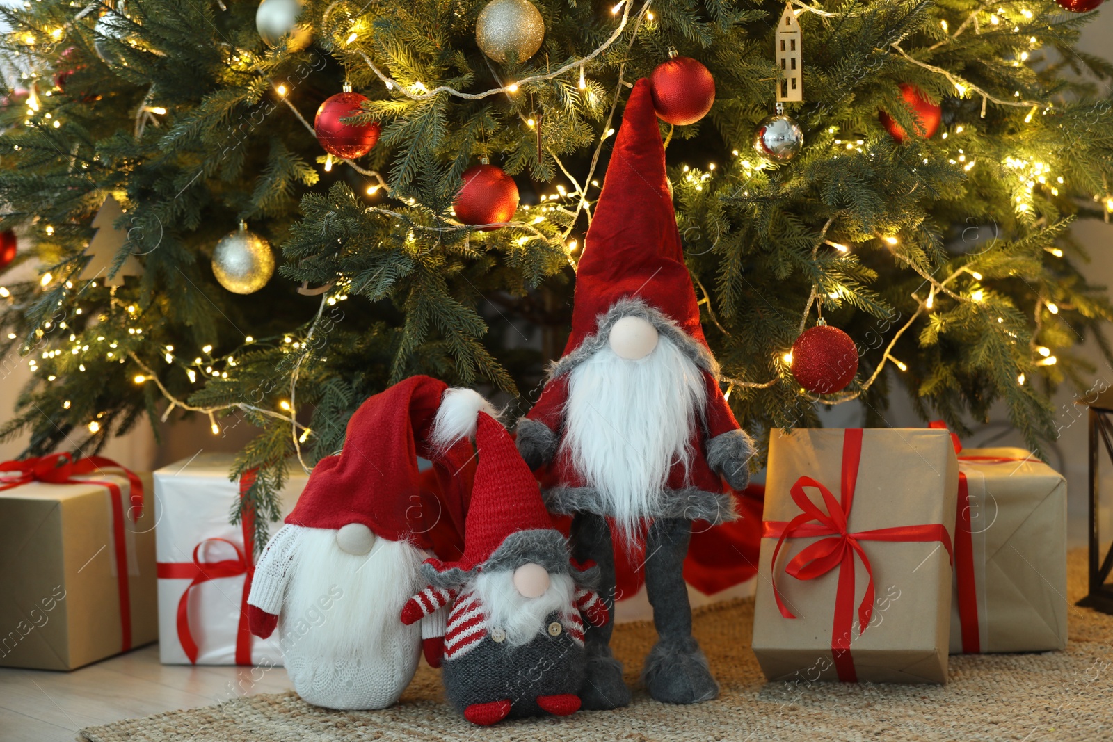 Photo of Funny decorative gnomes and gift boxes under Christmas tree indoors