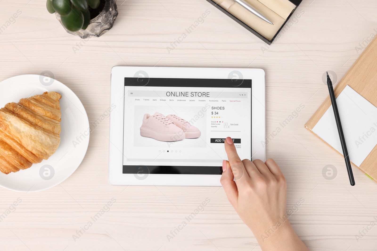 Photo of Woman with tablet shopping online at white wooden table, top view