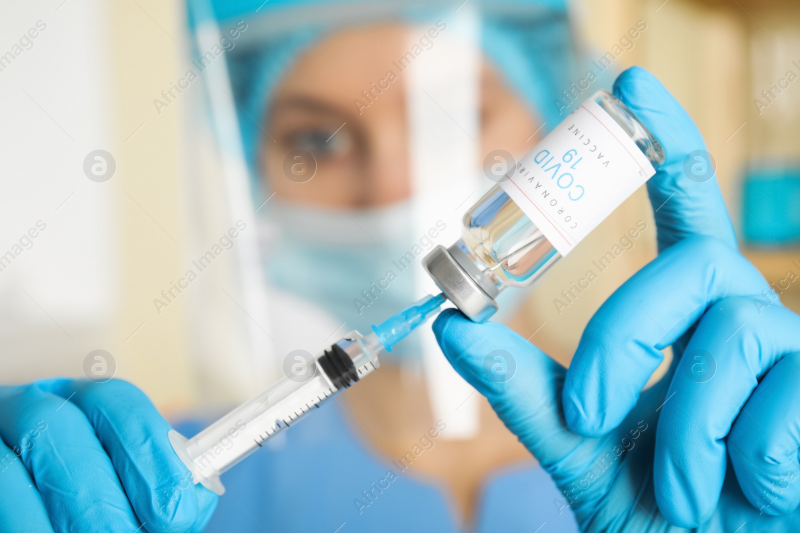 Photo of Doctor filling syringe with vaccine against Covid-19 in hospital, focus on hands