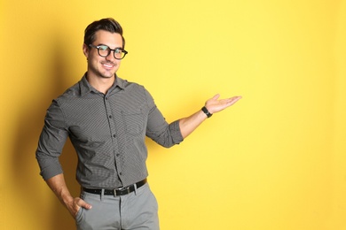 Photo of Young male teacher with glasses on yellow background. Space for text