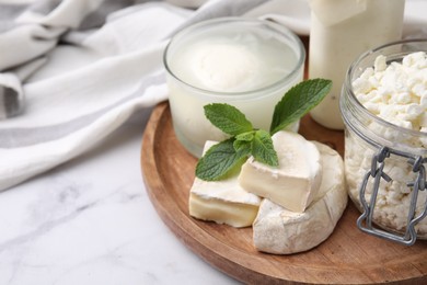 Different dairy products and mint on white marble table