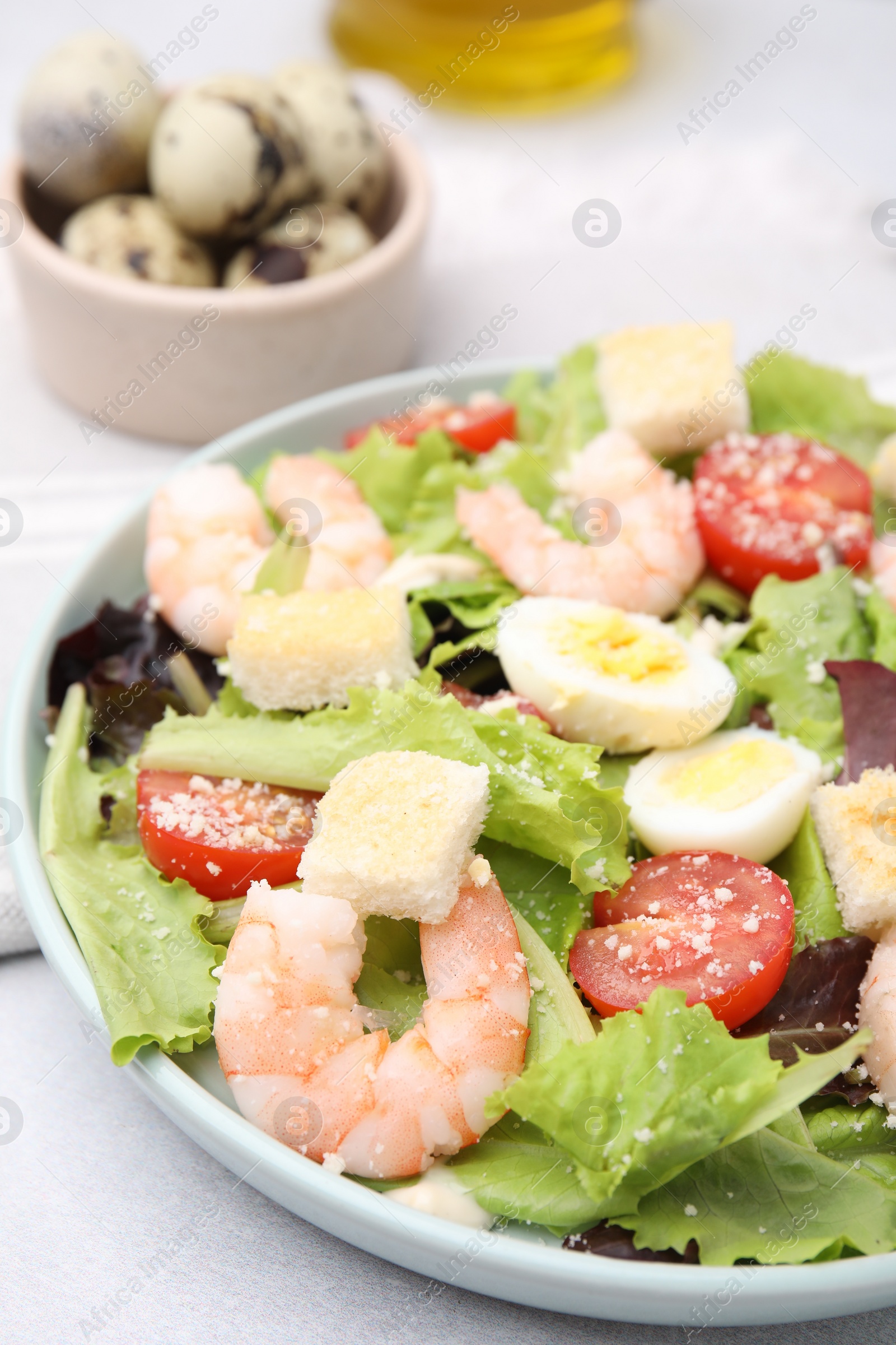 Photo of Delicious Caesar salad with shrimps on light table