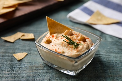 Delicious homemade hummus in glass bowl on wooden table