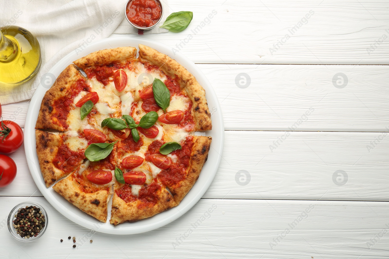 Photo of Delicious Margherita pizza and ingredients on white wooden table, top view. Space for text