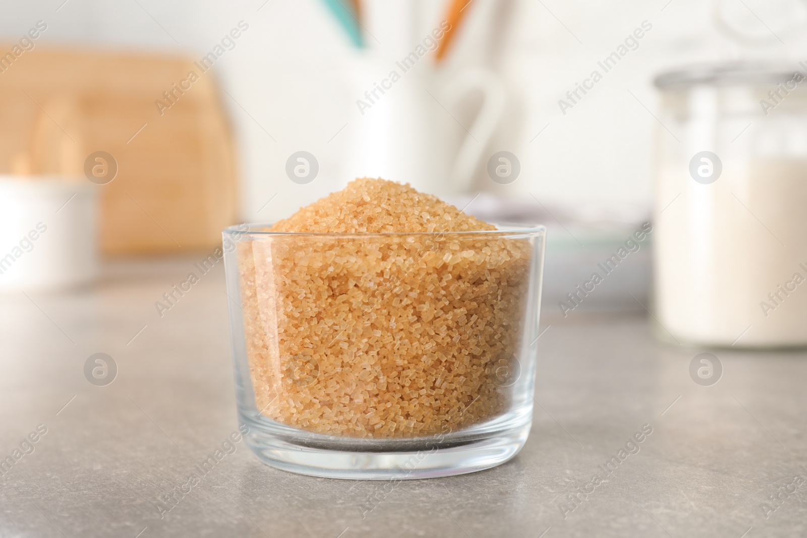 Photo of Glass bowl with brown sugar on grey table