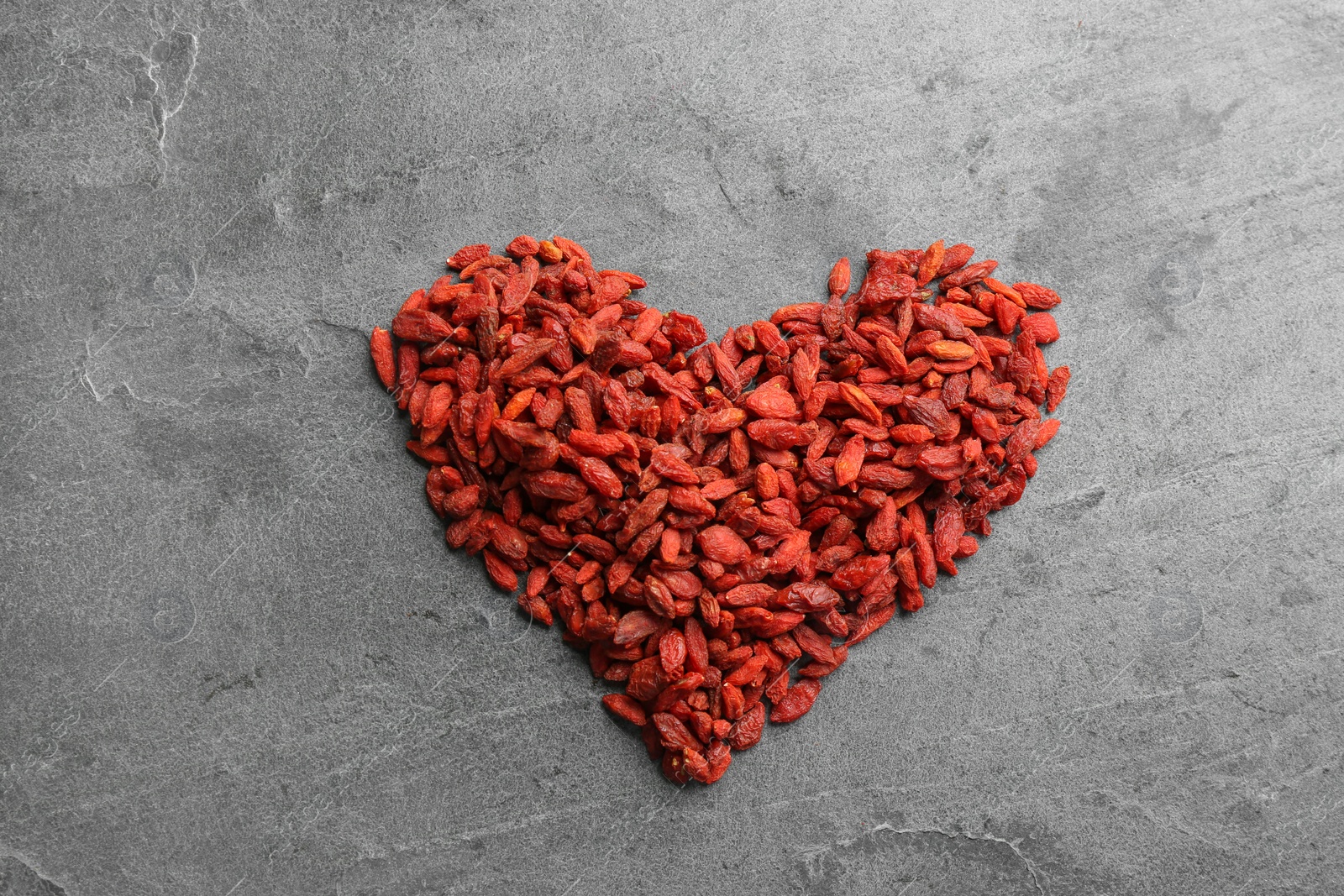 Photo of Heart made of dried goji berries on grey table, top view. Healthy superfood