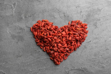 Photo of Heart made of dried goji berries on grey table, top view. Healthy superfood