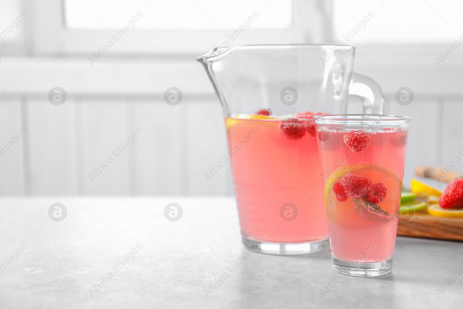 Photo of Jug and glass of fresh lemonade with berries on table