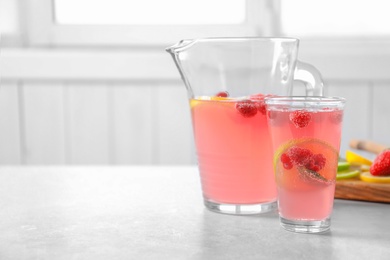 Photo of Jug and glass of fresh lemonade with berries on table