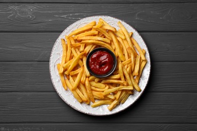 Tasty french fries with ketchup on black wooden table, top view