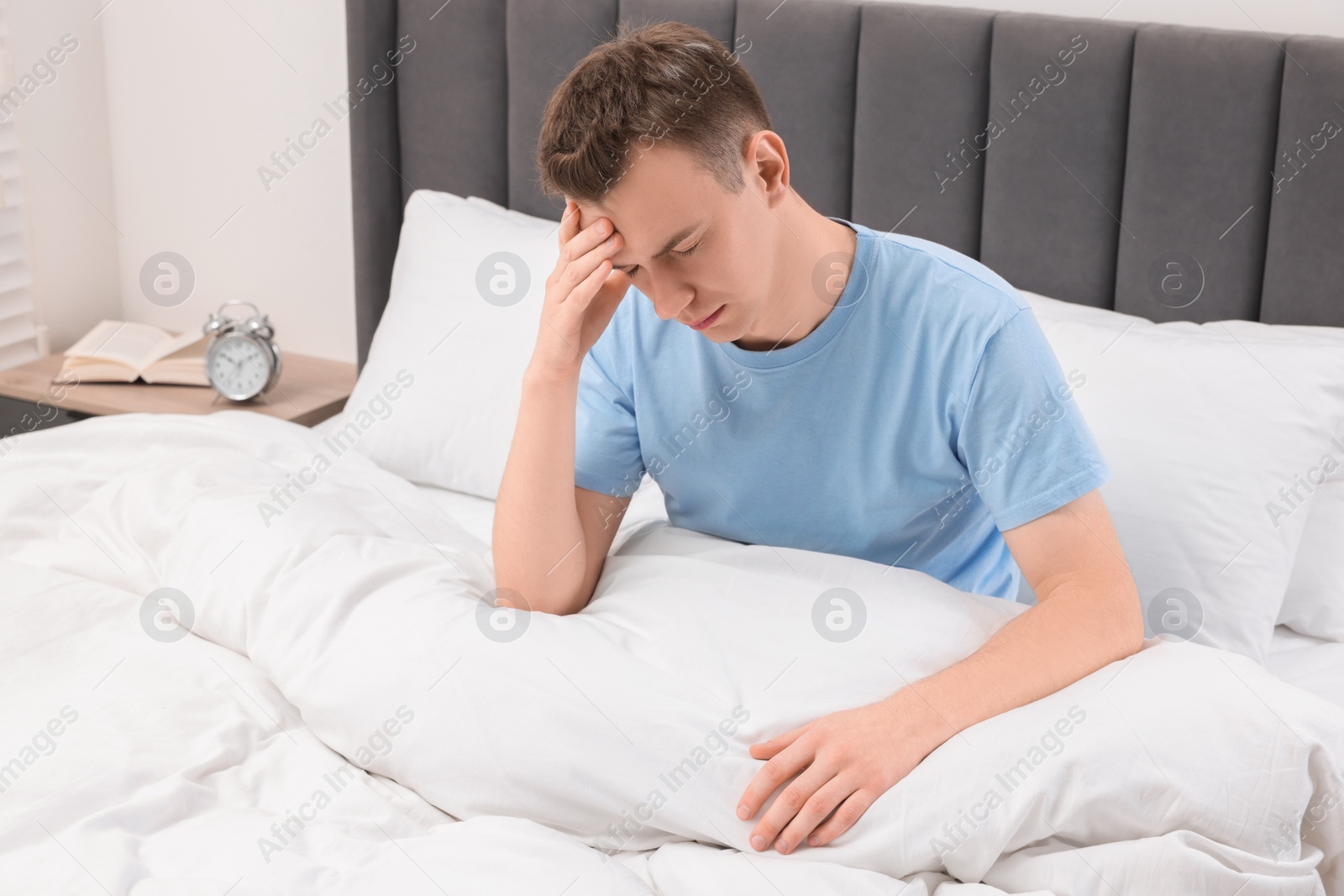 Photo of Sad man suffering from headache in bed indoors