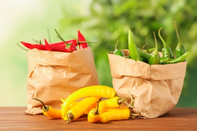 Paper bags with chili peppers on table against blurred background