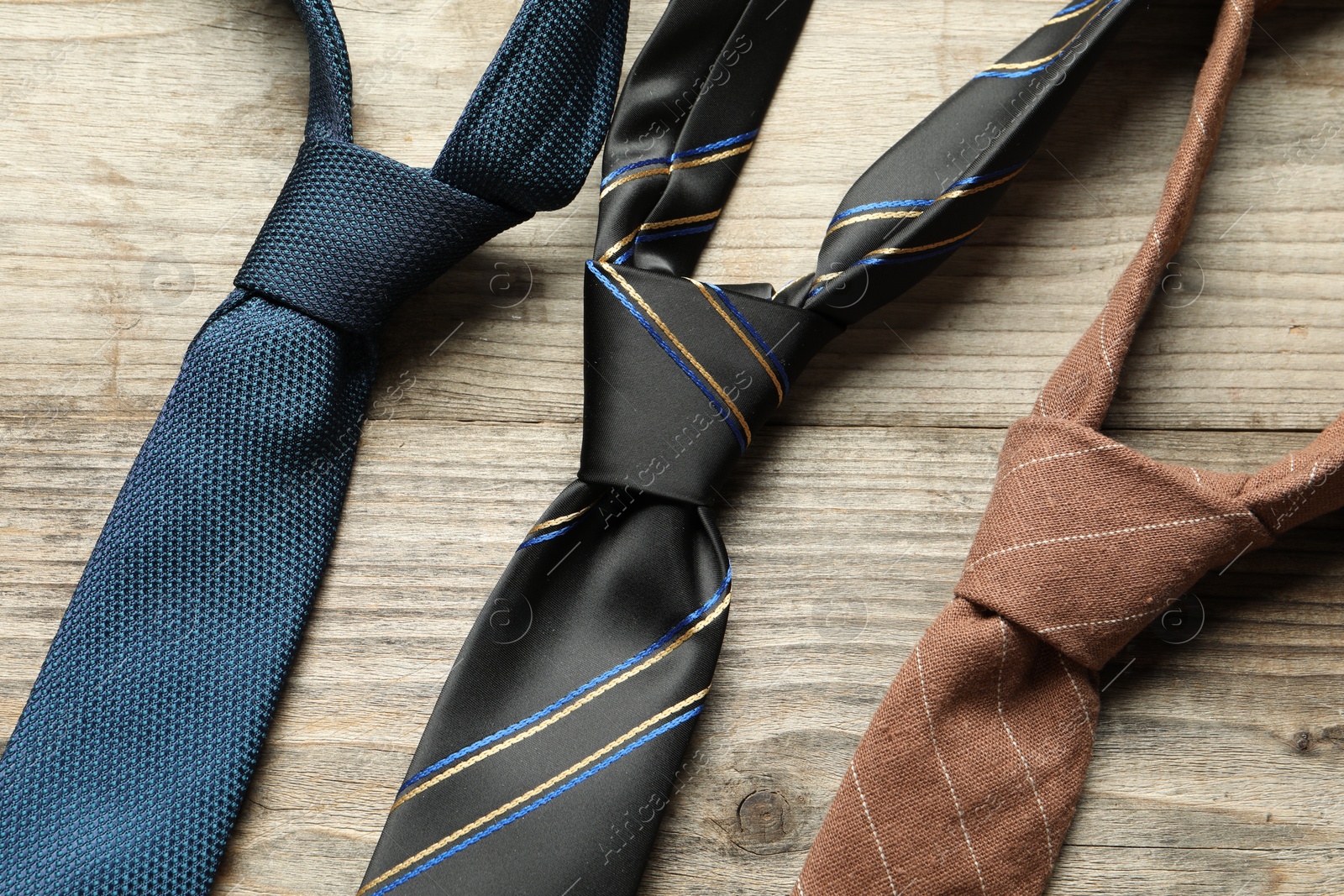 Photo of Different neckties on light wooden table, flat lay