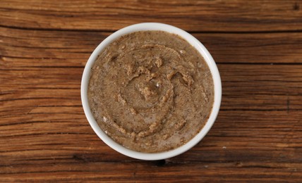 Delicious nut butter in bowl on wooden table, top view