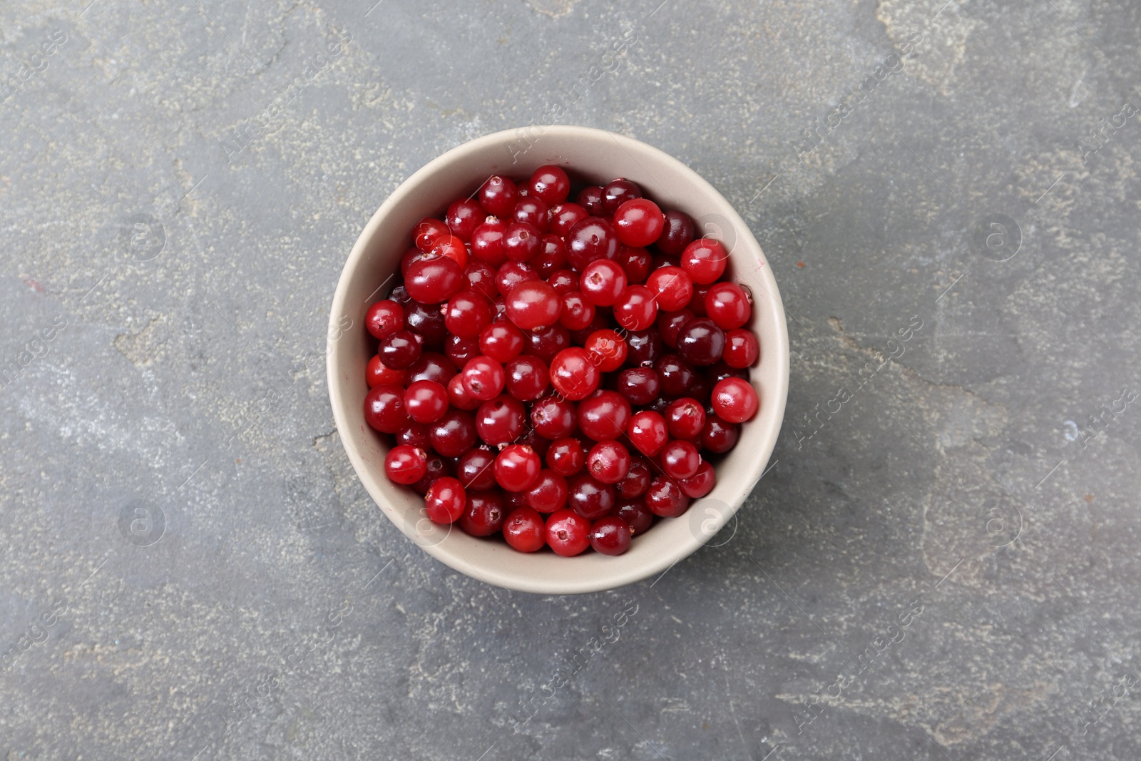 Photo of Fresh ripe cranberries in bowl on grey table, top view