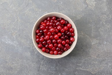 Photo of Fresh ripe cranberries in bowl on grey table, top view