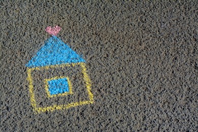 Photo of House with heart drawn by blue and yellow chalk on asphalt, space for text