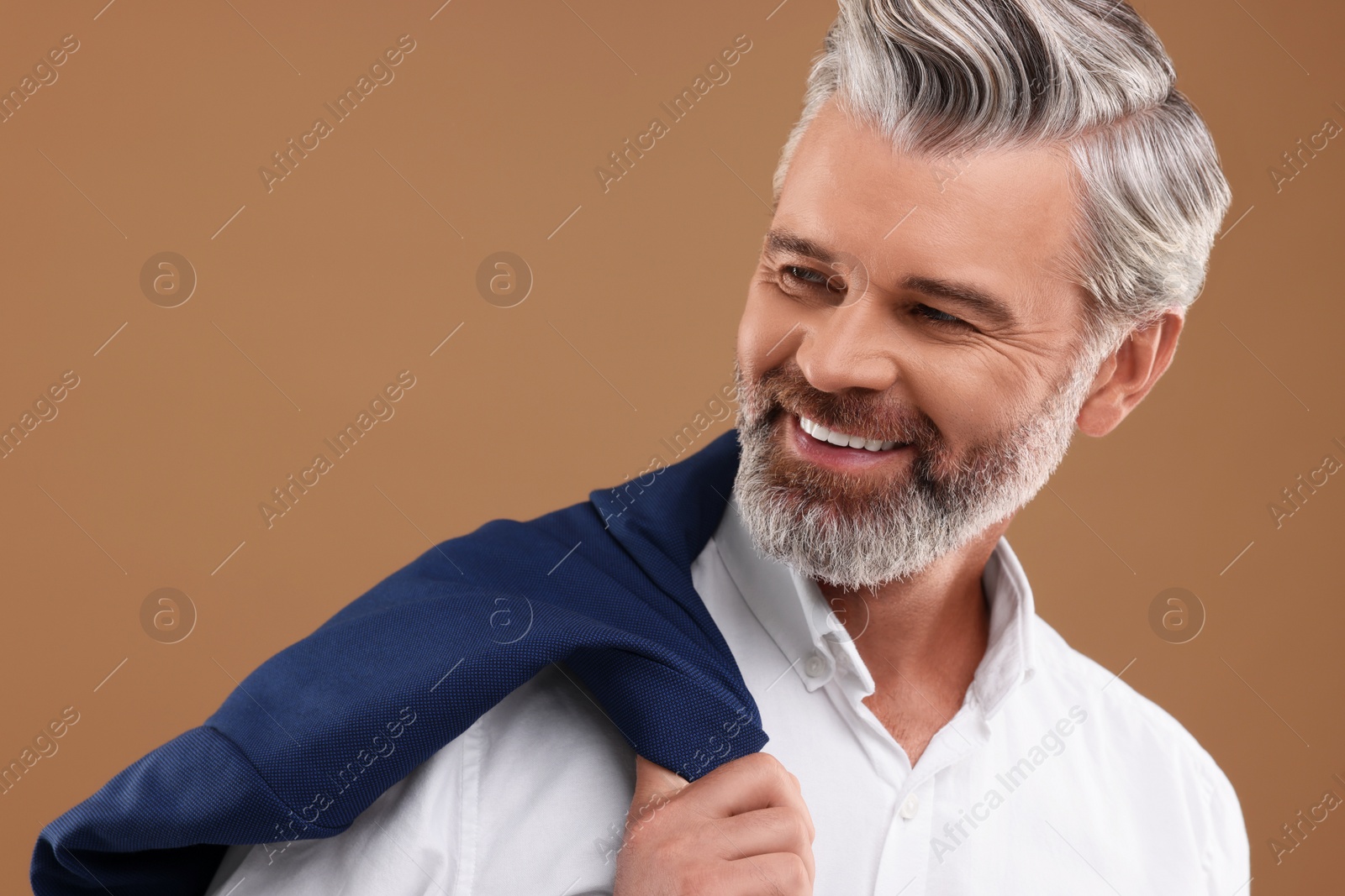 Photo of Portrait of smiling man with beautiful hairstyle on light brown background. Space for text