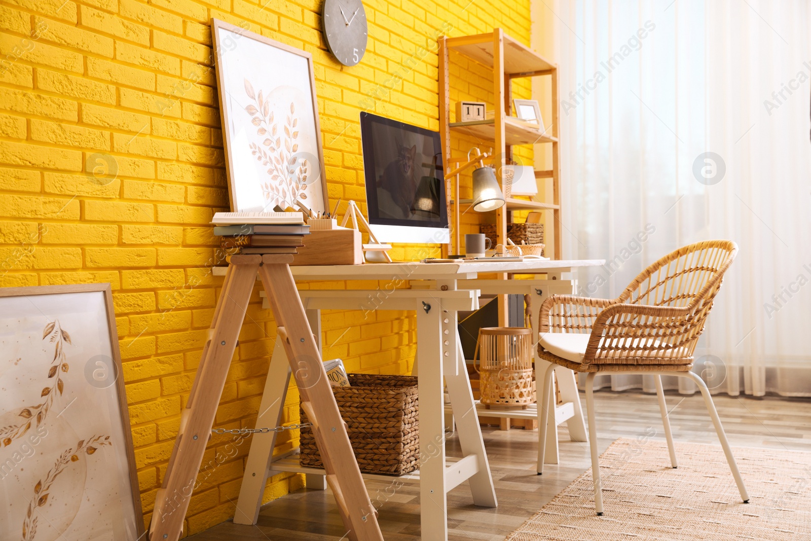 Photo of Stylish home office interior with comfortable workplace near yellow brick wall