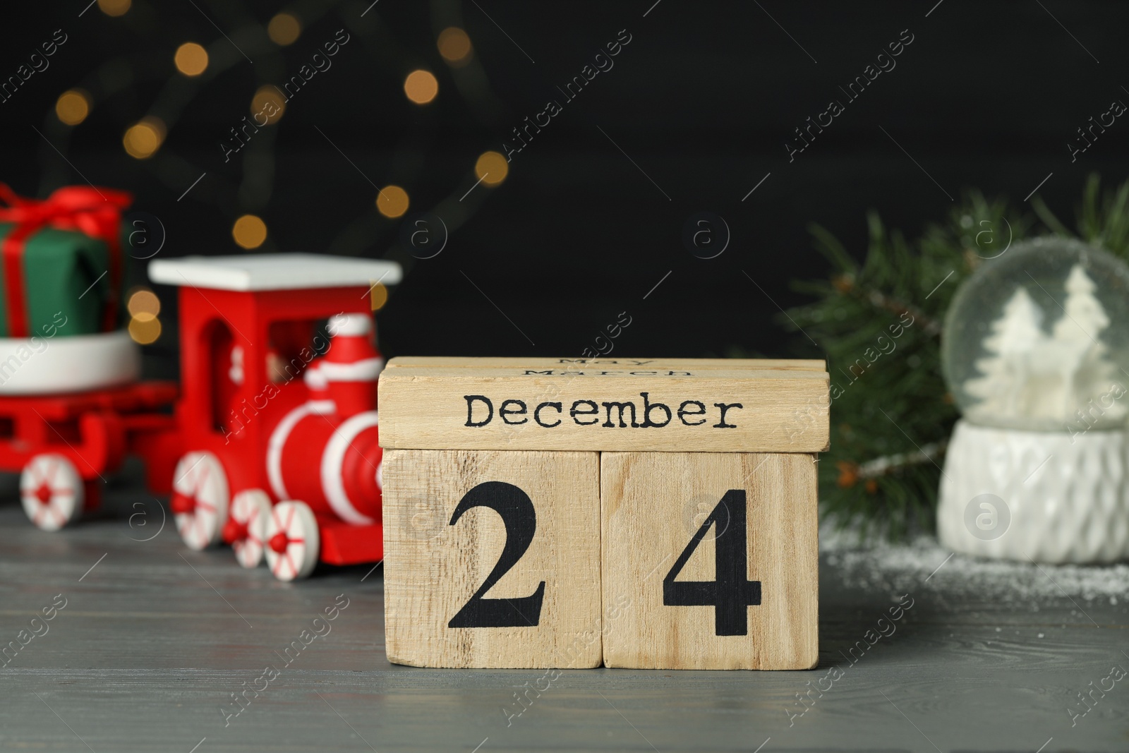 Photo of December 24 - Christmas Eve. Wooden block calendar and decor on table against blurred festive lights