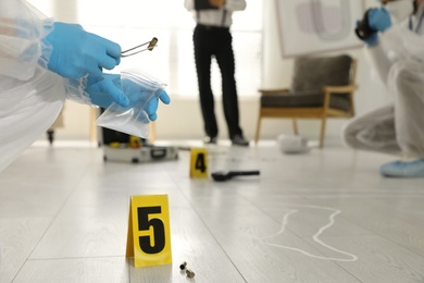 Photo of Investigators working at crime scene in messy room, closeup