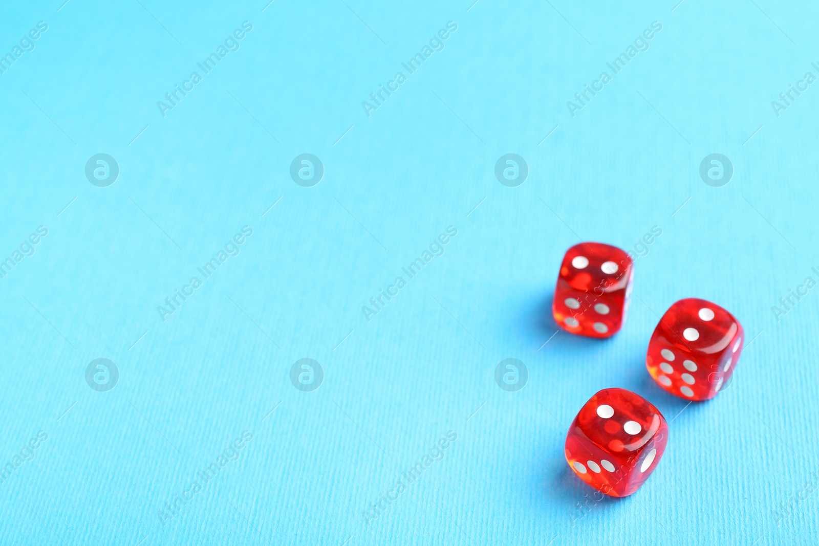 Photo of Three red game dices on light blue background. Space for text