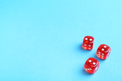 Photo of Three red game dices on light blue background. Space for text